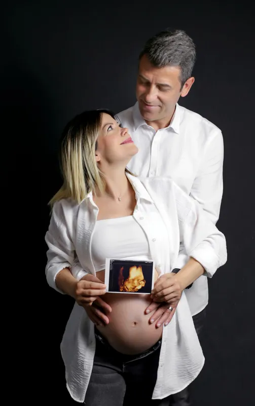 Bebek ultrason görüntüsünü karın önünde tutan gülümseyen anne ve baba