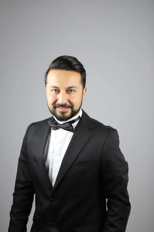 Siyah smokin ve papyonlu güler yüzlü beyefendi stüdyo portresi
