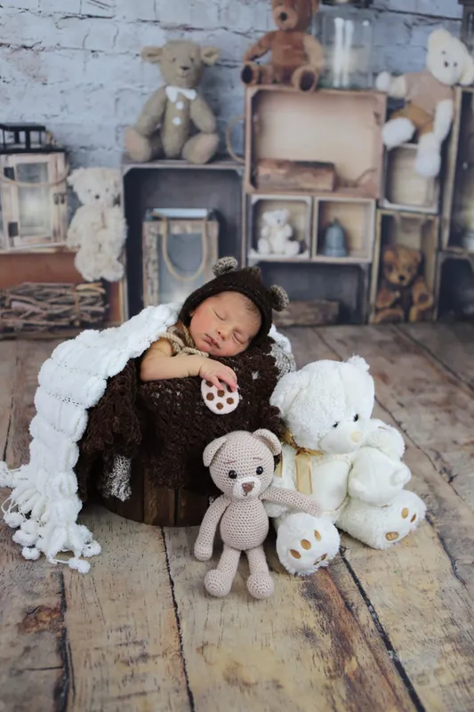 Ahşap dekor içinde peluş ayıcıkların kucağında mışıl mışıl uyuyan bebek